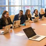 Home A diverse team of business professionals collaborating in a modern meeting room.